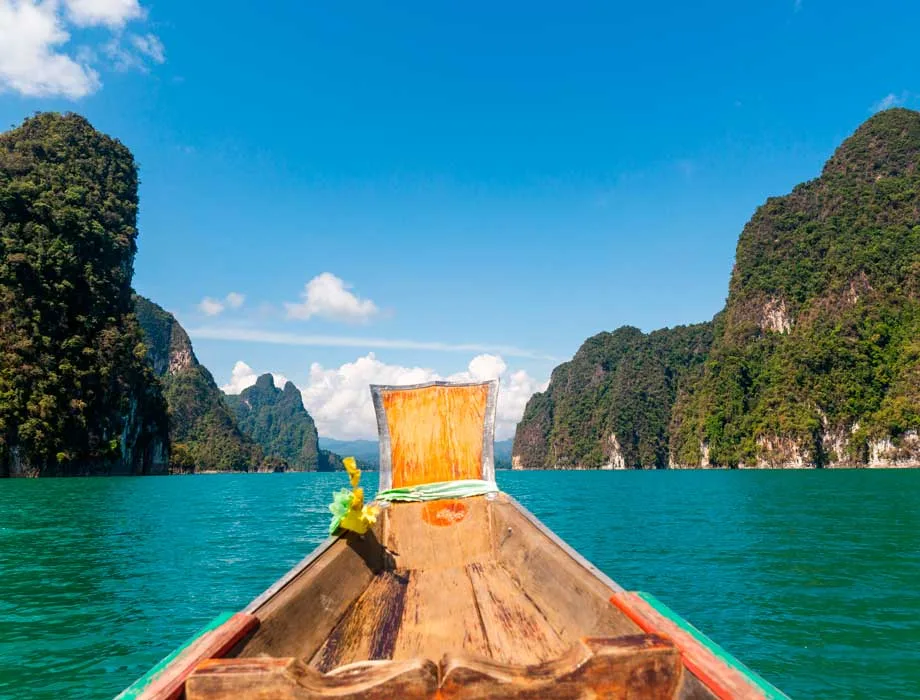 Longtail boat on the emerald Cheow Lan Lake under towering karsts