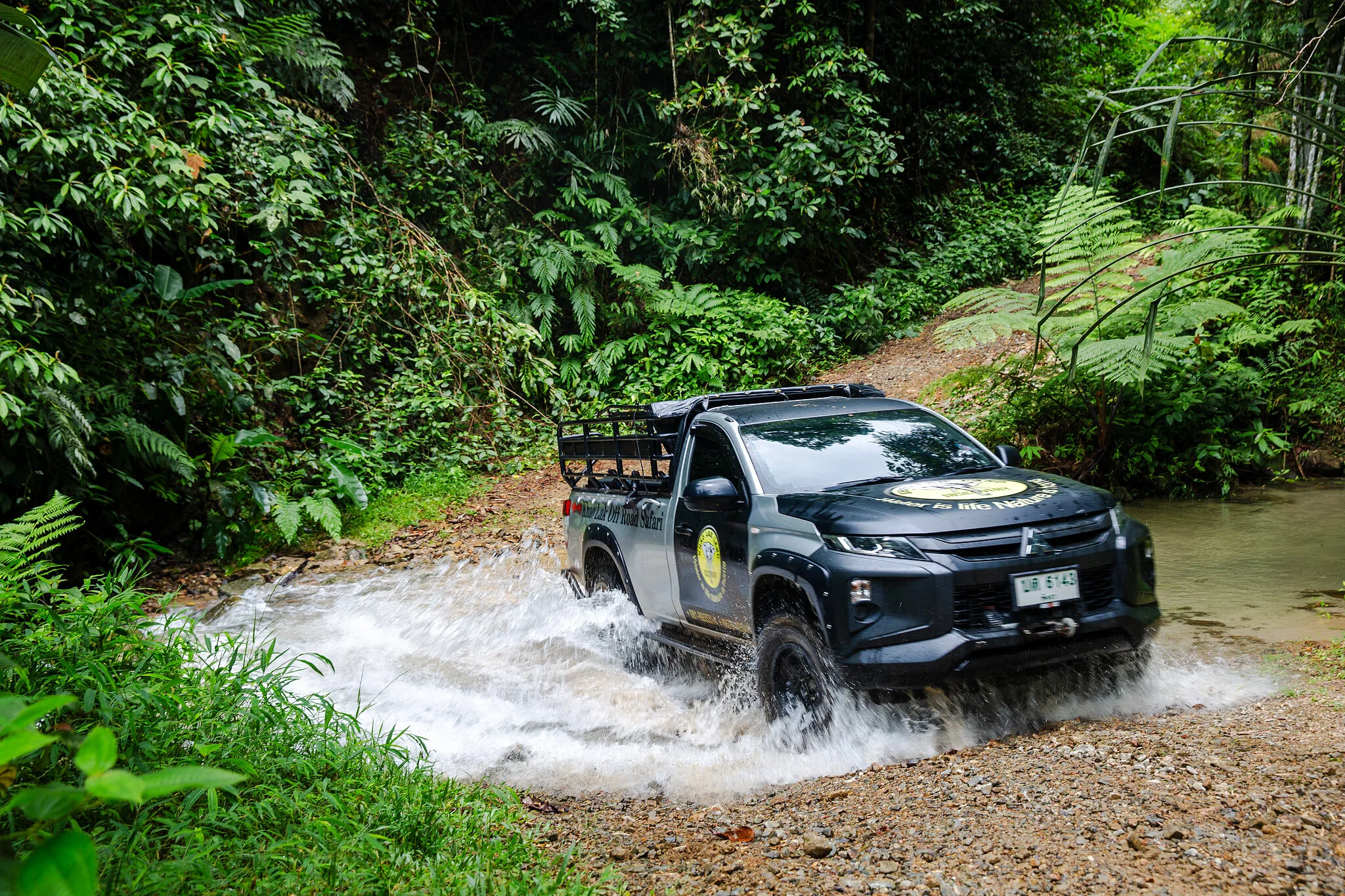 Off-road 4x4 splashing through a jungle stream crossing in the Khao Lak rainforest