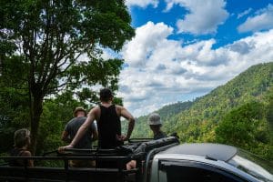 Gäste auf der Ladefläche des Safari-Trucks mit Blick über bewaldete Berge bei Khao Lak