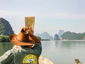 Longtail boat cruising through Phang Nga Bay limestone karsts