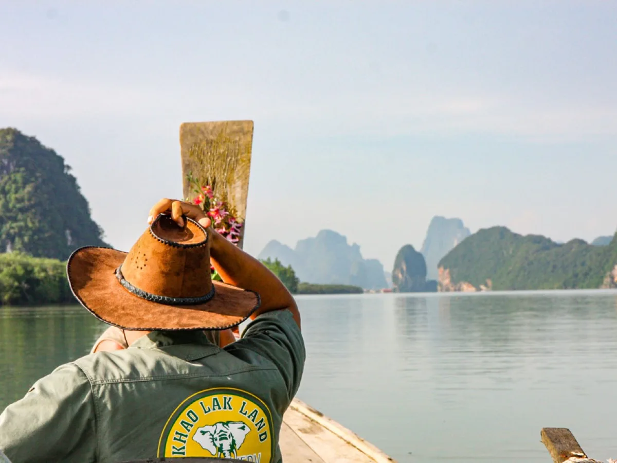 Longtail boat crossing the calm water of Phang Nga Bay at dusk
