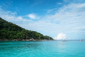 Speedboats anchored off a forested granite island in calm turquoise water, Similan Islands, Thailand
