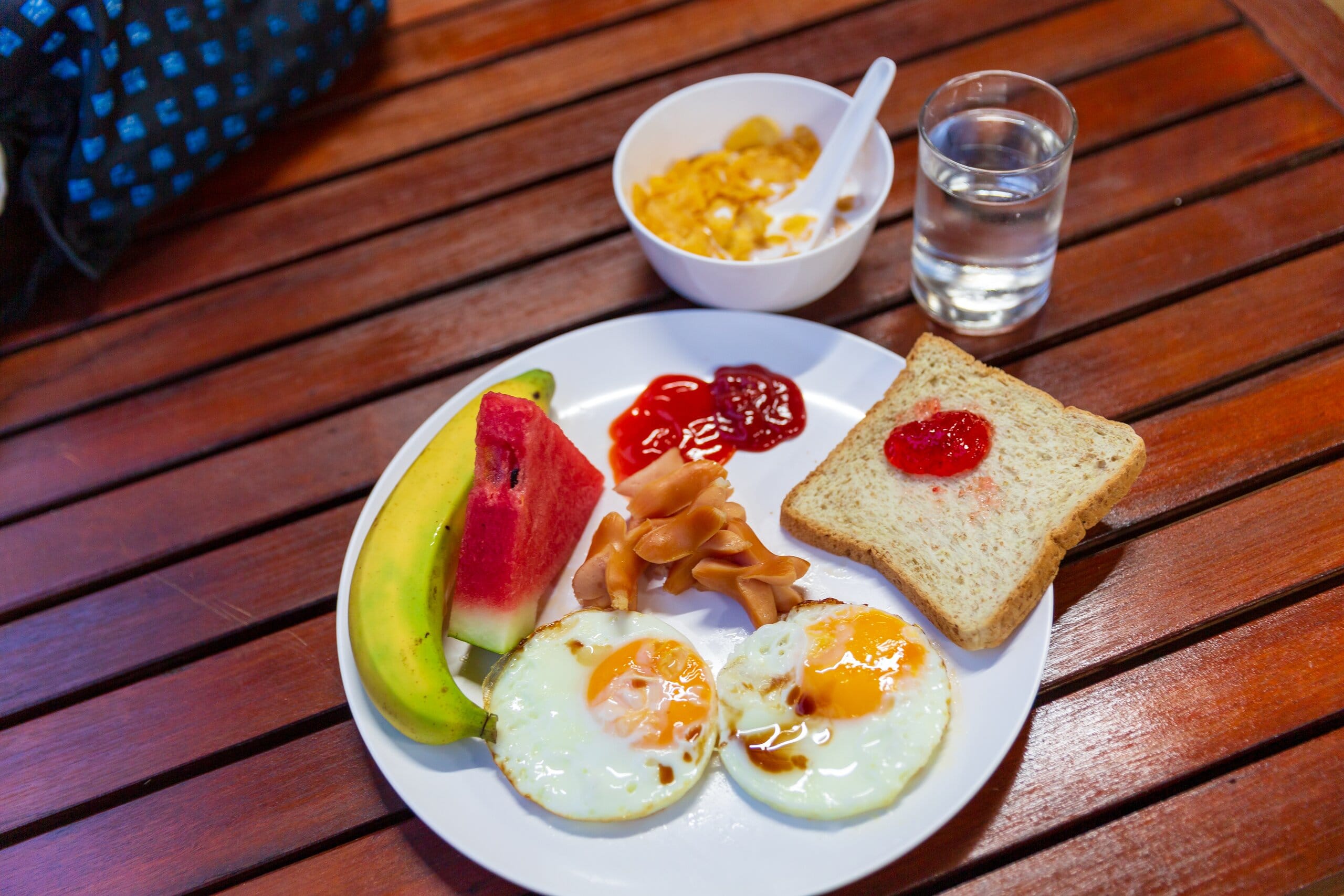 Breakfast plate with fried eggs, toast, fruit and cereal at the pier lounge before the Similan Islands speedboat trip
