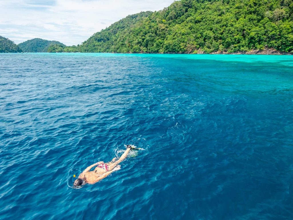 Group snorkeling above a shallow coral reef at Surin Islands