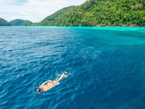Group snorkeling above a shallow coral reef at Surin Islands
