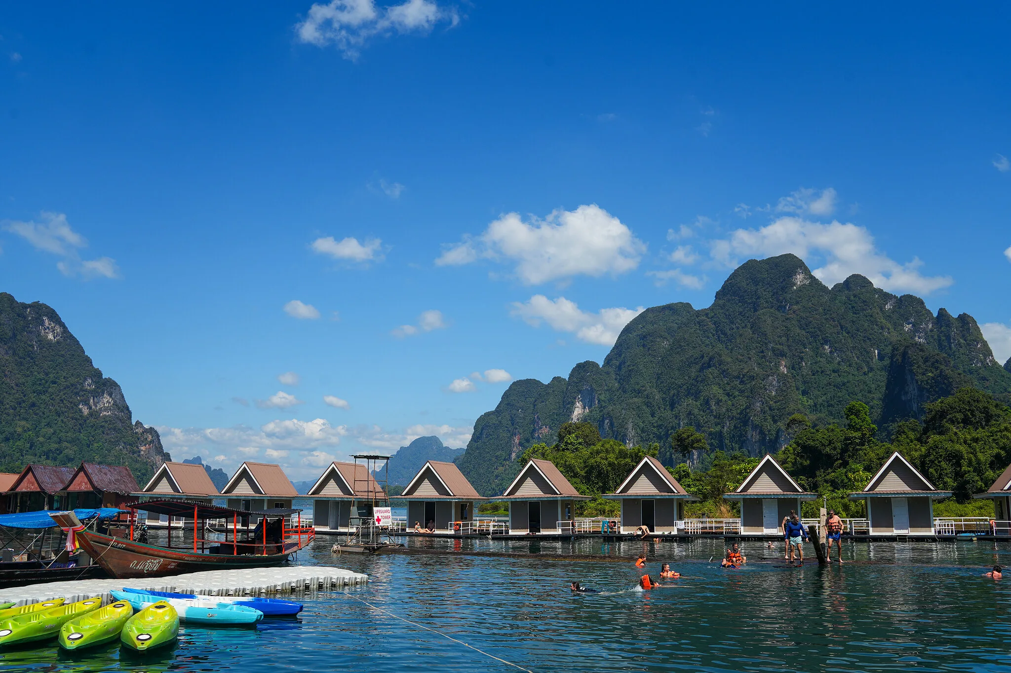 Schwimmende Floßhäuser und Kajaks unter dschungelbedeckten Karstgipfeln auf dem Cheow-Lan-See, Khao Sok