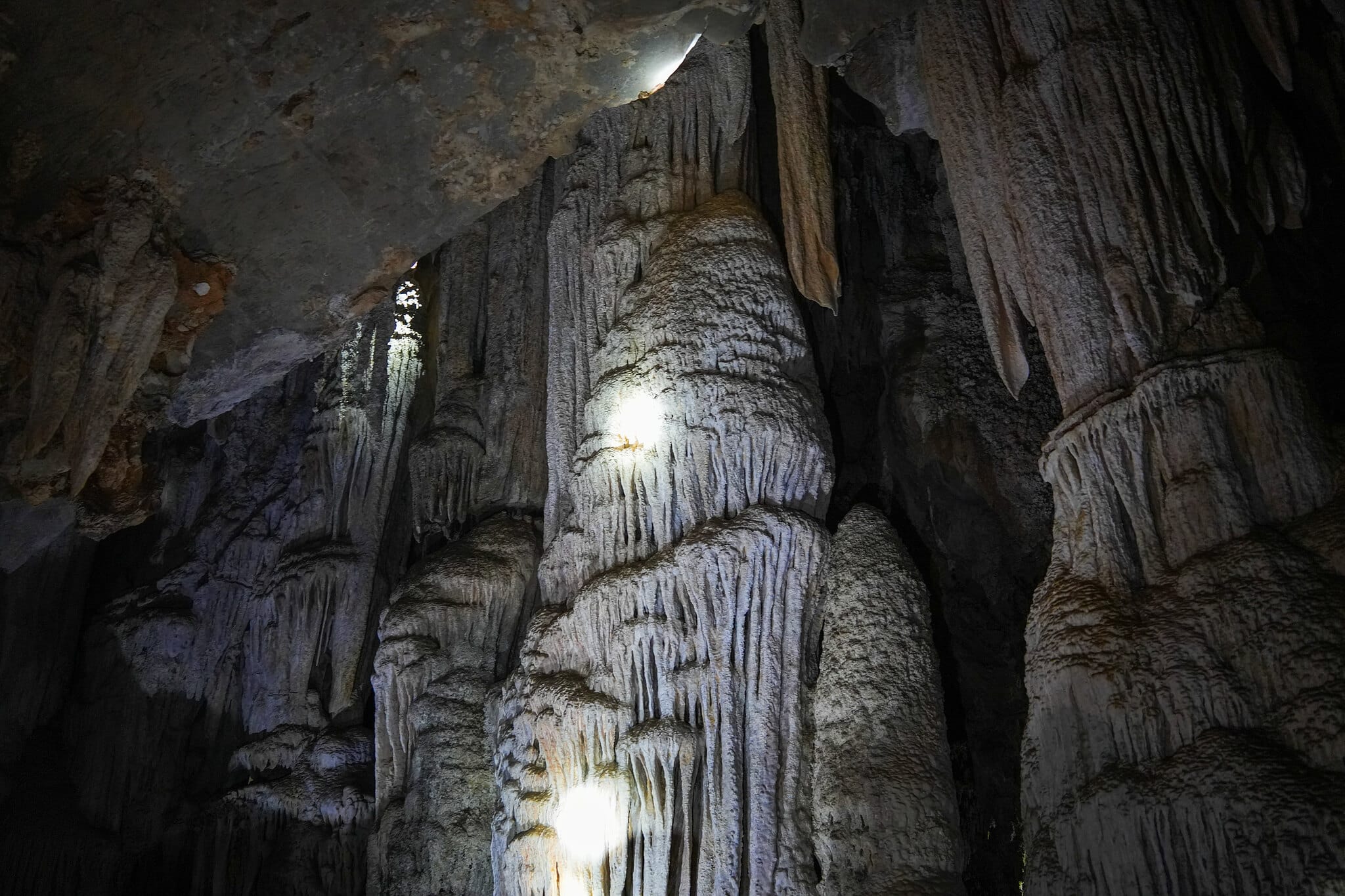 Stalactites and flowstone lit by torchlight inside a limestone cave at Cheow Lan Lake, Khao Sok
