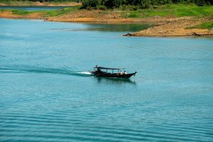 Traditional longtail boat crossing the calm turquoise water of Cheow Lan Lake, Khao Sok National Park