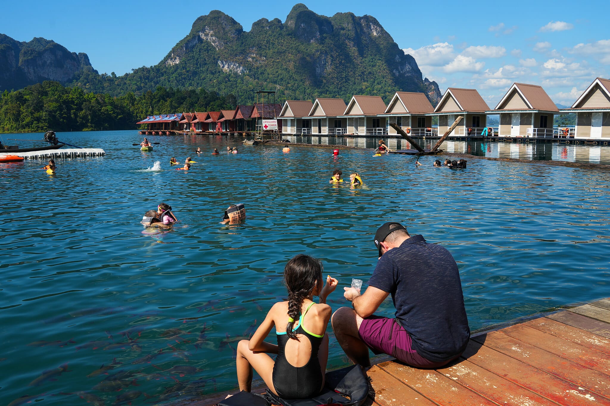 Guests swimming in the lake beside floating raft-house bungalows at Cheow Lan Lake, Khao Sok
