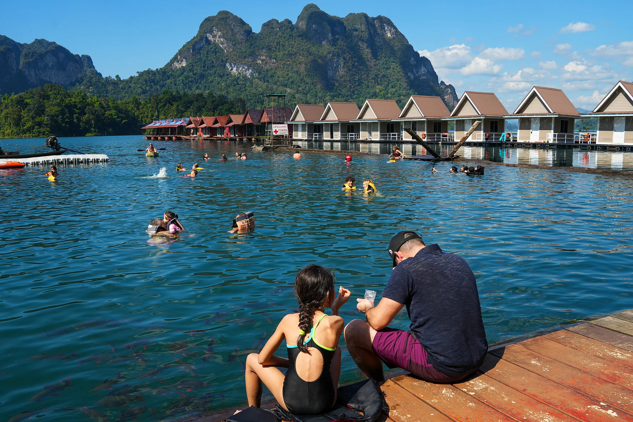 Gäste schwimmen im See neben schwimmenden Floßhaus-Bungalows am Cheow-Lan-See, Khao Sok