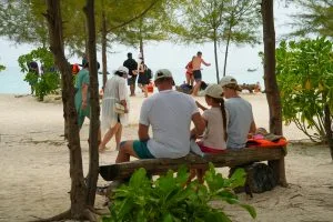 Family relaxing in the shade of casuarina trees on the white-sand beach of Bamboo Island