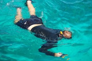 Snorkeler with mask and fins swimming face-down in clear turquoise water at the Surin Islands