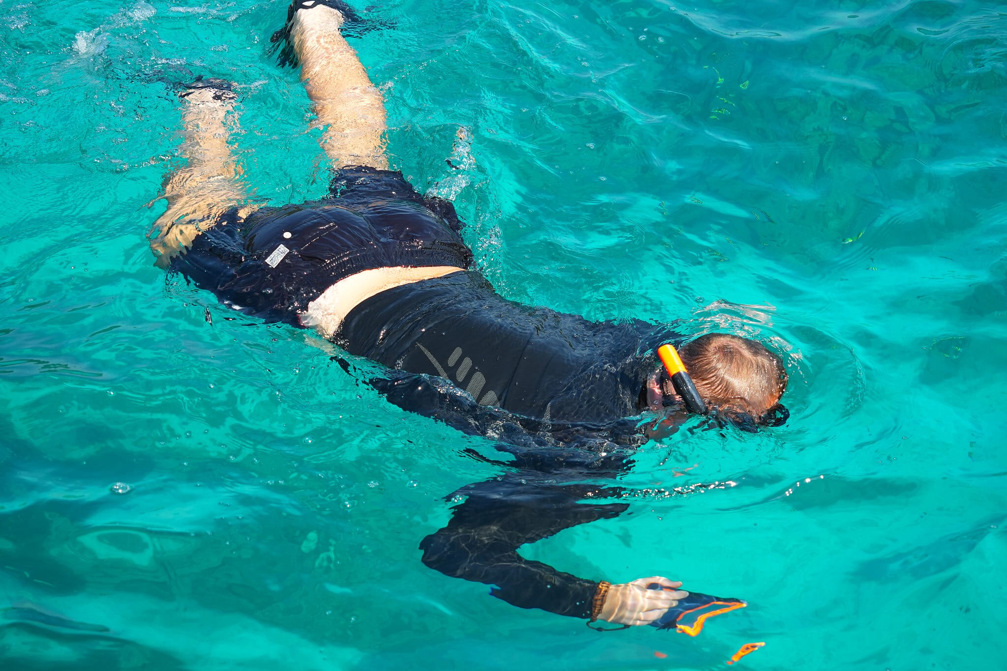 Snorkeler with mask and fins swimming face-down in clear turquoise water at the Surin Islands