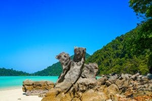 Weathered granite rocks on a white-sand beach with turquoise water and jungle hills, Surin Islands