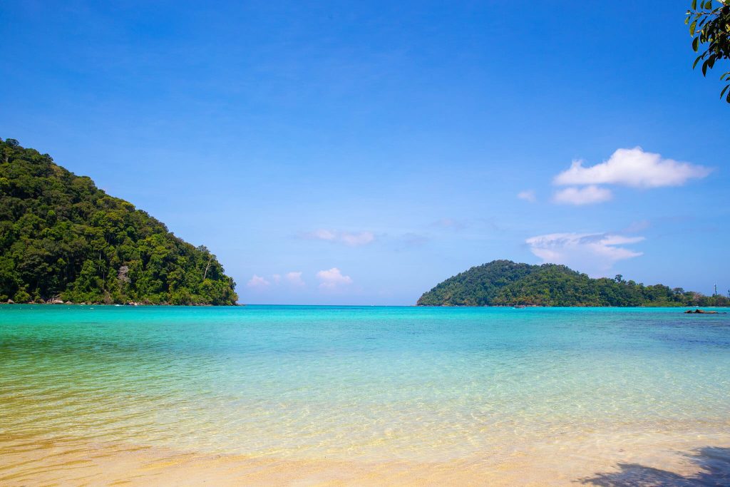 Transfer Khao Lak zum Kuraburi-Pier - surin islands snorkeling 06 Ruhige türkisfarbene Bucht zwischen grünen Inseln unter blauem Himmel im Mu-Ko-Surin-Nationalpark, Thailand