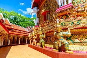 Golden guardian statues and ornate gilded walls at Wat Bang Riang temple, Phang Nga