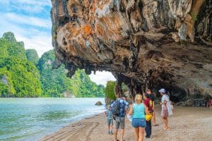 Visitors on the beach beneath the overhanging limestone cliff of James Bond Island, Phang Nga Bay