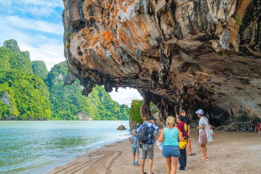 Visitors on the beach beneath the overhanging limestone cliff of James Bond Island, Phang Nga Bay