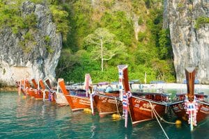 Colourful longtail boats moored below limestone cliffs on the Krabi island-hopping tour