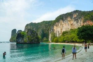 Visitors wading along the shallow turquoise shore beneath towering cliffs on Koh Hong, Krabi