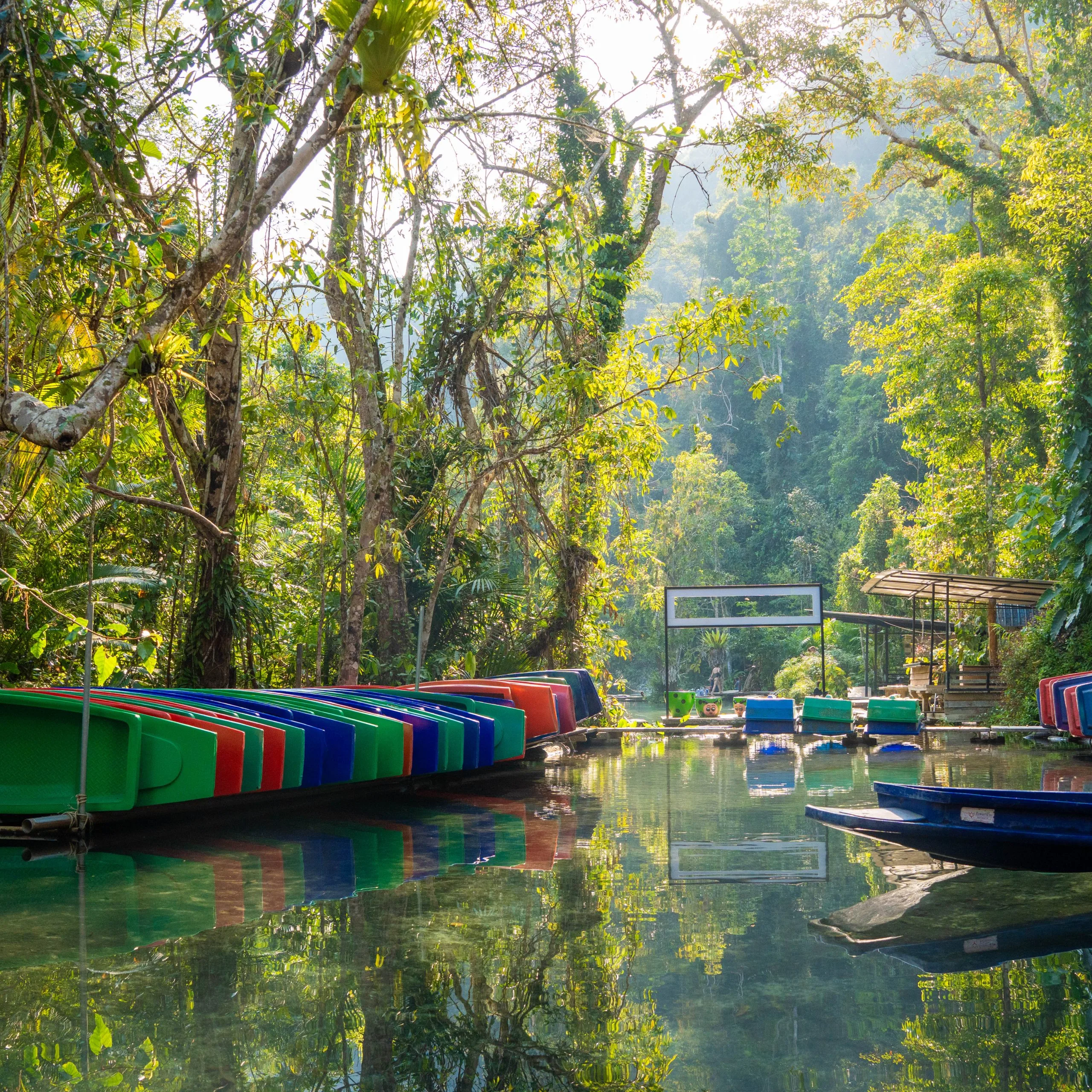 Jungle canal with colourful kayaks and boats moored at a pier