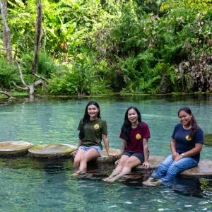 Three guests sitting on stepping stones in a clear jungle pool