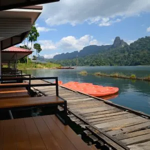 Wooden deck of a floating bungalow with orange kayaks on Cheow Lan Lake