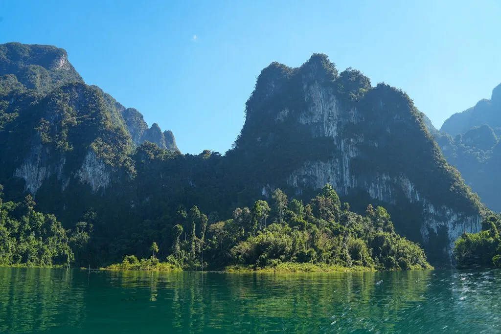 Sheer limestone mountains rising above the turquoise water of Cheow Lan Lake in Khao Sok National Park