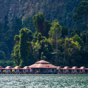 Schwimmende Bungalows auf dem See unter einer dschungelbewachsenen Felswand