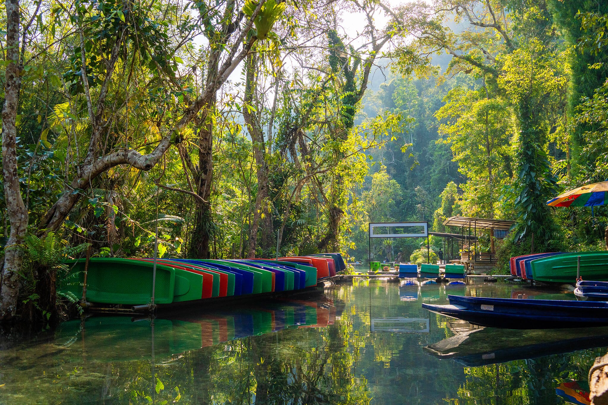 Bunte Longtail-Boote in einer klaren Dschungellagune bei Khao Sok