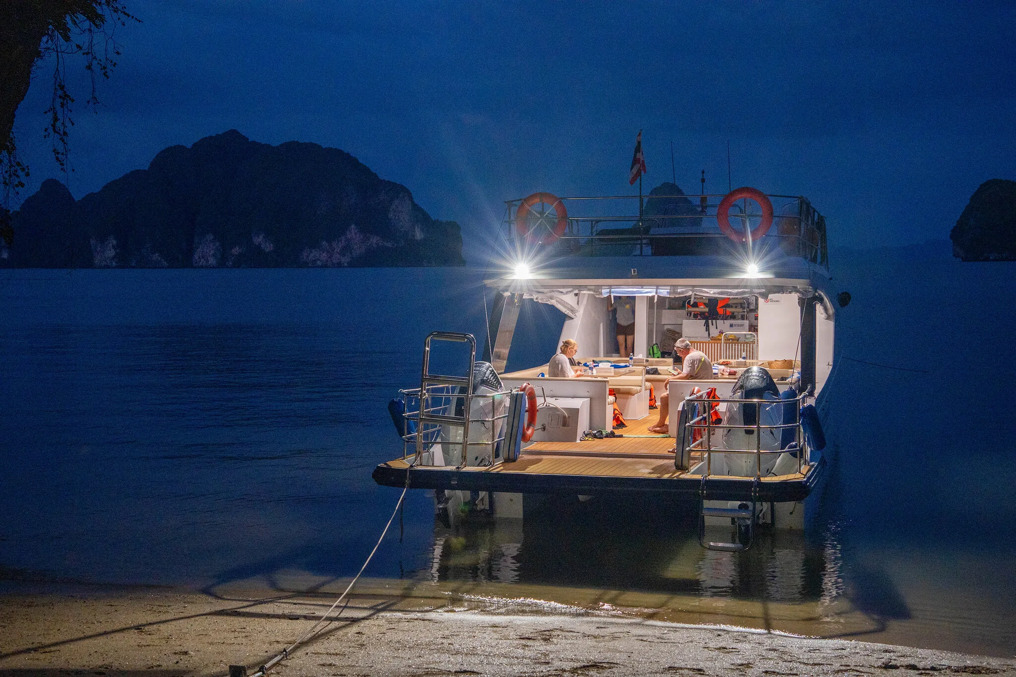 Catamaran de croisière illuminé sur la plage à l'heure bleue avant le dîner à Koh Hong, baie de Phang Nga