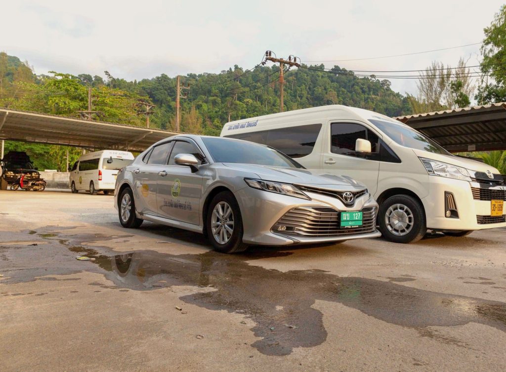 A Toyota Camry and a Toyota Commuter minivan from the Khao Lak Land Discovery fleet, parked with forested hills behind