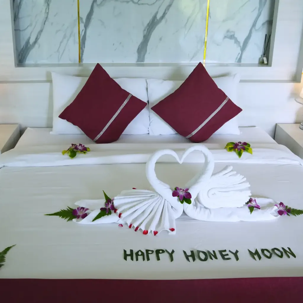Bed dressed with honeymoon towel swans and rose petals