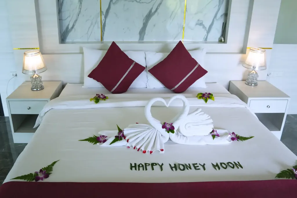 Bed dressed with honeymoon towel swans and rose petals