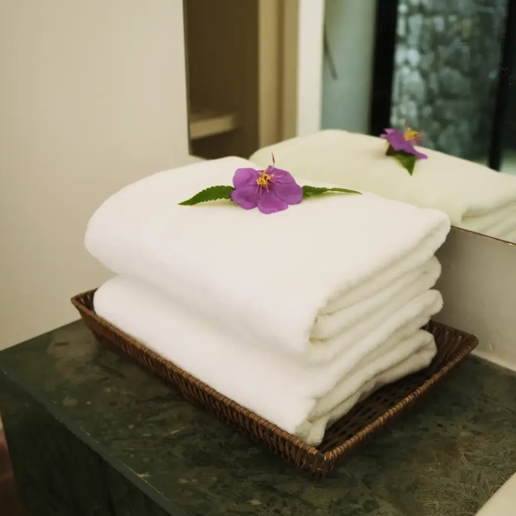 Folded towels with an orchid on the vanity