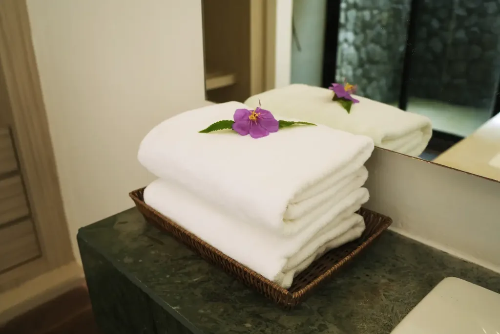 Folded towels with an orchid on the vanity