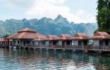 A row of floating bungalows moored on the emerald water of Cheow Lan Lake beneath towering limestone karst peaks in Khao Sok National Park