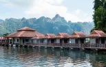 A row of floating bungalows moored on the emerald water of Cheow Lan Lake beneath towering limestone karst peaks in Khao Sok National Park
