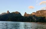 Late afternoon light on jagged limestone peaks rising above the still water of Cheow Lan Lake