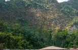Jungle-covered limestone cliffs rising above the calm emerald water of Cheow Lan Lake beside a floating raft house