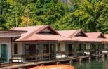 Orange kayaks moored alongside a floating raft house on Cheow Lan Lake in Khao Sok National Park