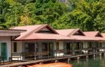 Orange kayaks moored alongside a floating raft house on Cheow Lan Lake in Khao Sok National Park