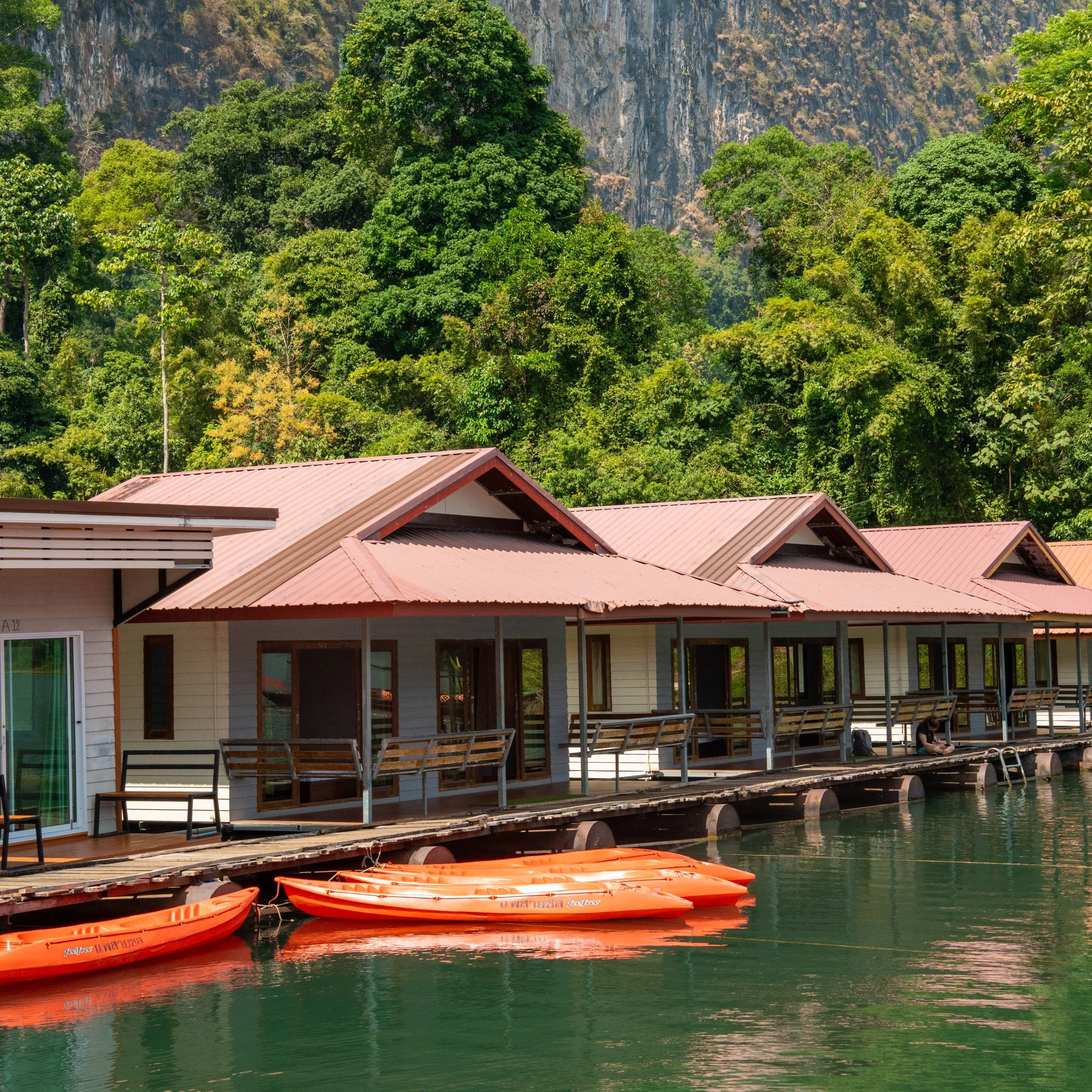 Orange kayaks moored alongside a floating raft house on Cheow Lan Lake in Khao Sok National Park