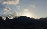 A longtail boat silhouetted against the sunrise beside limestone mountains on Cheow Lan Lake