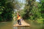 A local guide poles a bamboo raft along a calm rainforest river during the Khao Lak national park safari