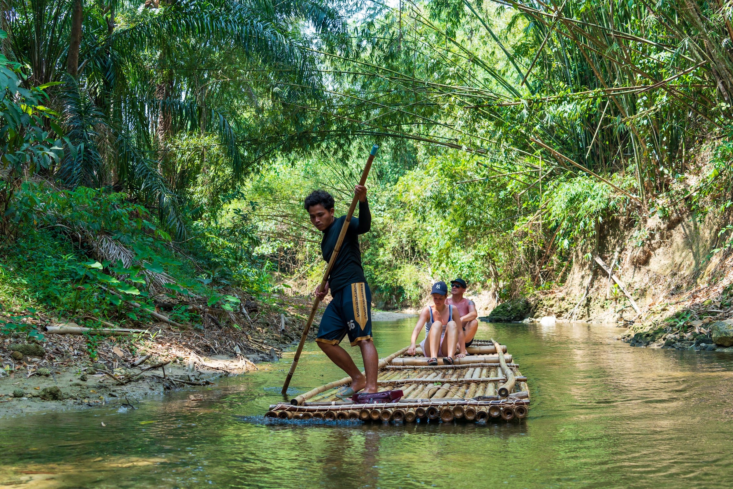 Guests drift downstream on a traditional bamboo raft through dense jungle on the Khao Lak safari tour