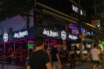 Brightly lit bar fronts glow in pink and blue neon along the Patong nightlife strip in Phuket