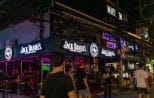 Brightly lit bar fronts glow in pink and blue neon along the Patong nightlife strip in Phuket