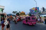 A pink tuk tuk passes the Welcome to Patong Beach arch at dusk on the Patong nightlife trip