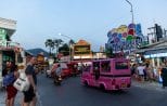 A pink tuk tuk passes the Welcome to Patong Beach arch at dusk on the Patong nightlife trip